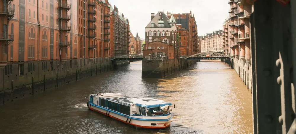 Hamburg: die Backsteinkontore der Speicherstadt an einem Kanal, mit einer Barkasse im Vordergrund