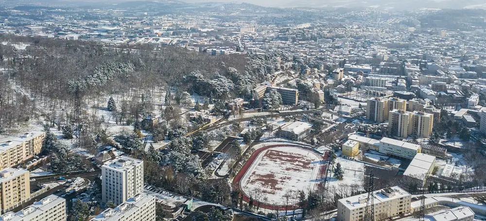 Vue aérienne de Saint-Étienne sous la neige : la ville, ses collines et le stade au premier plan
